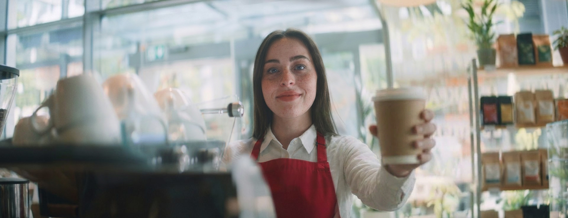 A friendly ExpoBaristi barista handing over a coffee